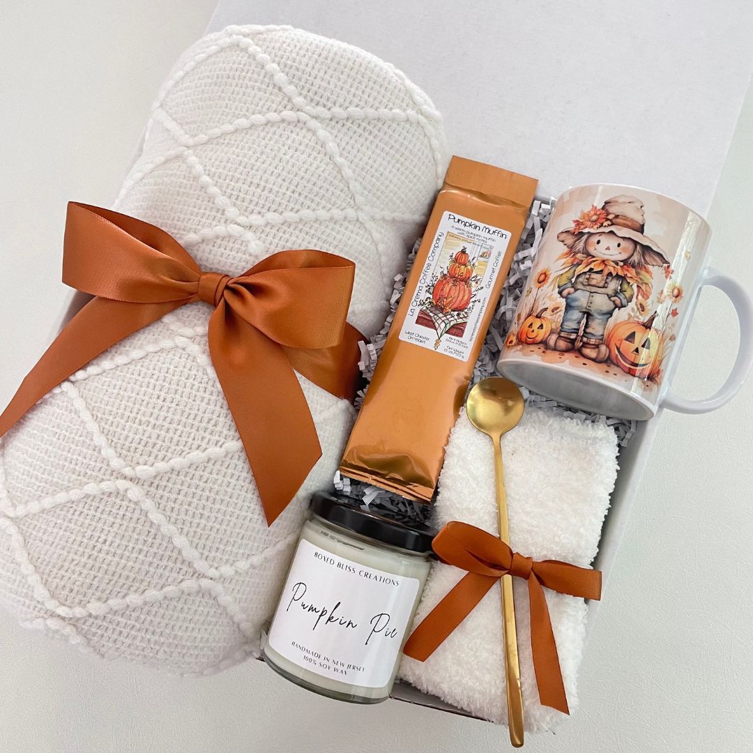 fall themed blanket with scarecrow mug, pumpkin scented candle, copper ribbons, pumpkin muffin coffee and golden spoon