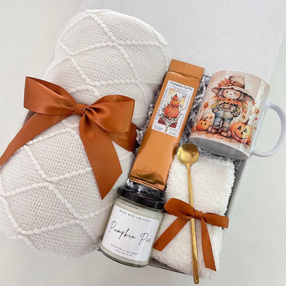 fall themed blanket with scarecrow mug, pumpkin scented candle, copper ribbons, pumpkin muffin coffee and golden spoon