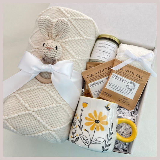 new baby gift box with blanket, baby gift rattle, yellow bee mug with flowers, soothing tea and fuzzy socks, all natural soy wax candle