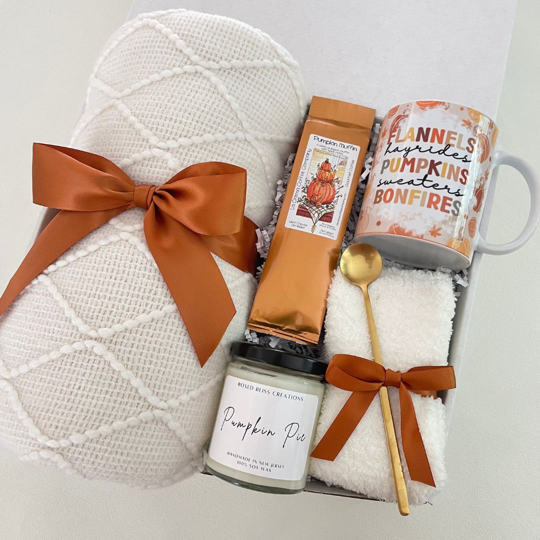 fall gift box with white blanket, pumpkin scented candle and copper colored bows